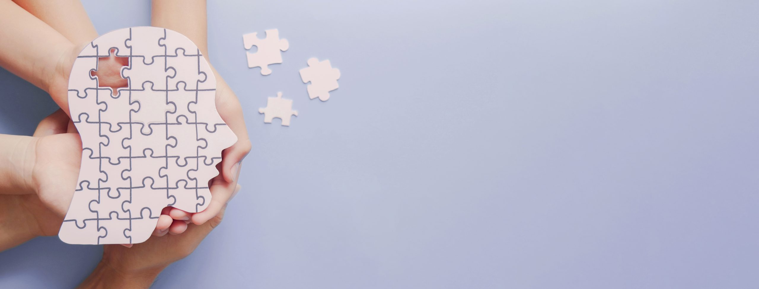 Hände halten einen Kopf aus Puzzleteilen