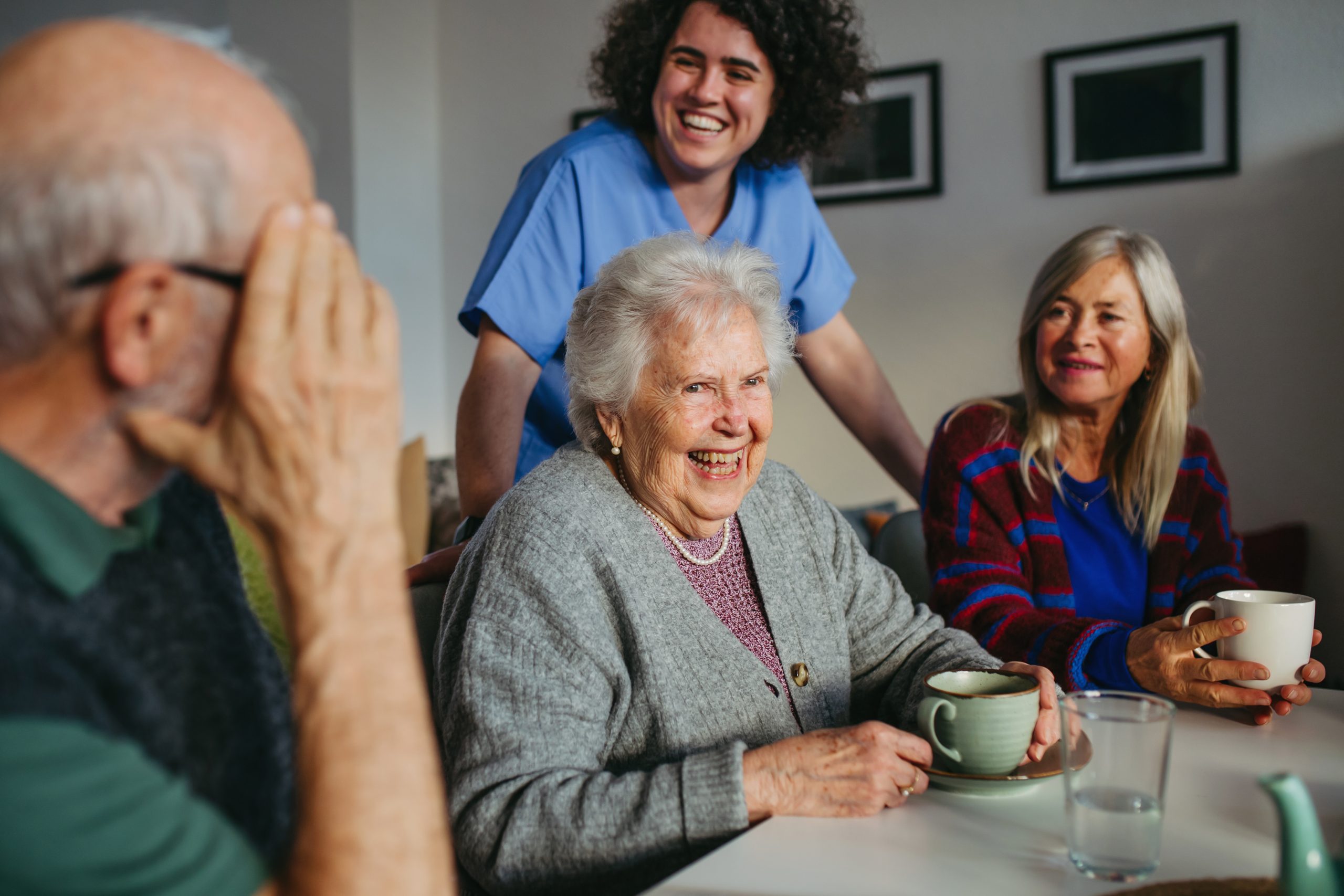 Ältere Menschen und eine Betreuungskraft lachen gemeinsam